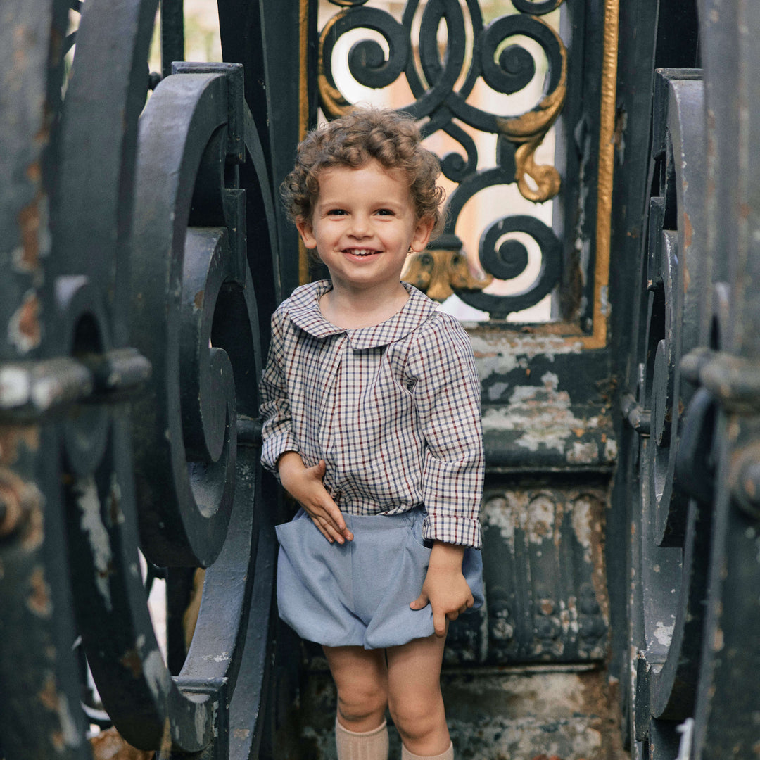 child standing in front of a fence with a tartan shirt